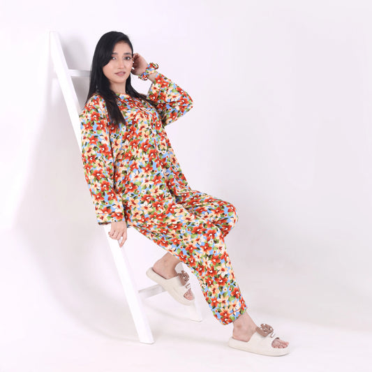 Woman wearing a colorful floral onesie sitting on a white chair against a white background